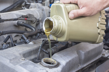 Fototapeta premium car worker changes, adds oil in avto. Concept maintenance car repair