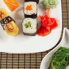 Sushi set and hiyashi wakame salad on a bamboo mat. View from above.