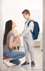 Young woman saying goodbye to her son before school