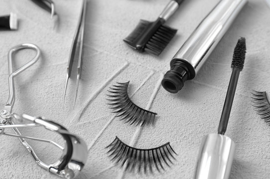 Composition with false eyelashes and cosmetic tools on grey background