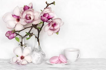 Zelfklevend Fotobehang Pink magnolia flowers bouquet with coffee cup and macarons on white wooden background © samael334