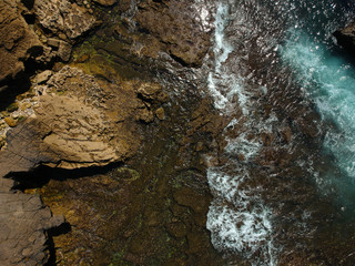 Aerial view of sea waves crash on the rocks in the coastline