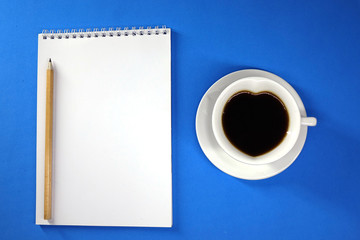 Obraz na płótnie Canvas Notepad and coffee on colored background top view