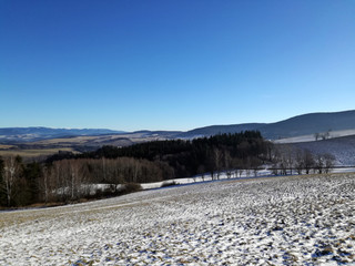 Fototapeta na wymiar View of snowy landscape, mountains and field, Czech republic