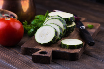 Zucchini with slices and onion on a wooden table.
