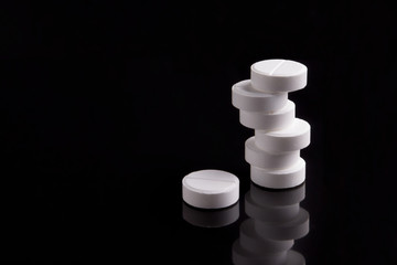 white pills on a black background, medicine, harm to health, addiction.