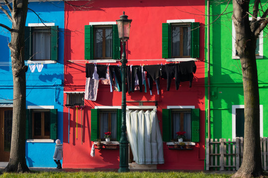Niña paseando delante casas de colores en Burano