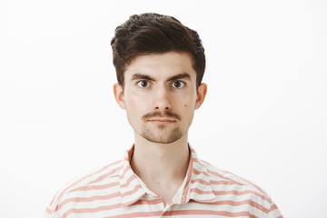 Close-up shot of calm and confident caucasian male model in striped shirt, standing casually at camera, being self-assured while volunteering to give blood, standing over gray background