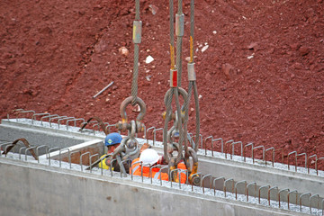Workers attaching wire strops to a concrete beam