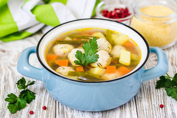 Turkey spinach meatball soup in a pot on white rustic background. Selective focus, space for text.