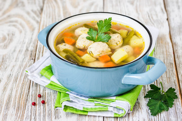 Italian minestrone meatball soup in a pot on white rustic background. Selective focus, space for text.