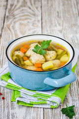 Cheesy parmesan meatball soup in a pot on white rustic background. Selective focus, space for text.