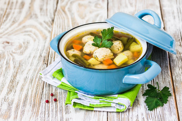 Mexican meatball soup in a pot on white rustic background. Selective focus, space for text.