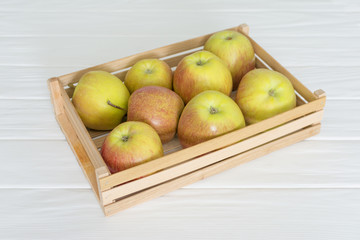 Wooden crate box full of fresh apples isolated on white table.