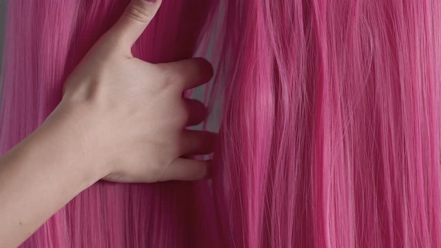 Closeup of pink hair creative colored texture Woman's hand take off half of hair texture and let it falling then