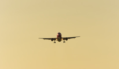 big commercial airplane at landing with sunset sky background