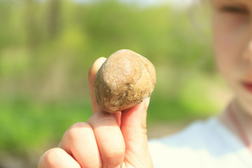 little girl holding a stone in her hand. The stone is a close-up. The girl does not focus