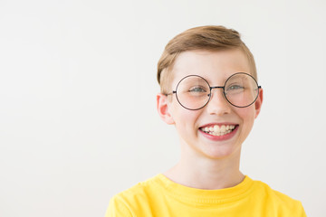 Handsome laughing teen boy with big glasses and yellow t-shirt