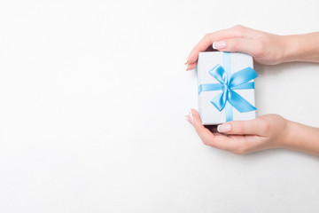 small present with blue ribbon bow in woman hands on white background. Sweet reward gift for holiday or birthday. free space concept