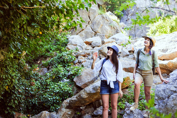 Two beautiful young girls travel in the mountains and enjoy the view of the landscape of green trees.