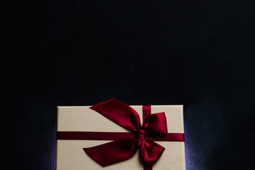 stylish luxury present for valentines day. gift box with rich red ribbon bow on dark background. love and romance. copyspace concept