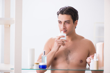 Young man is getting prepared for working day in bathroom