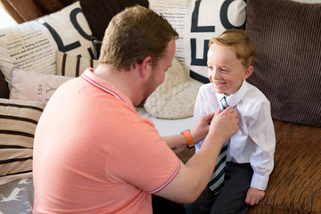 Father getting son dressed for school at home