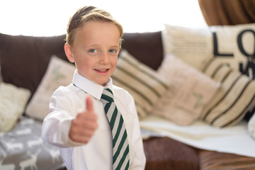Young boy dressed in new uniform and ready for school, whilst holding thumb up