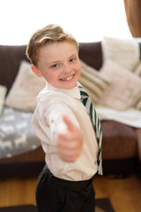 Young boy dressed in new uniform and ready for school, whilst holding thumb up