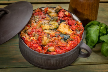 Ratatouille in ceramic pot with Basil on wooden table
