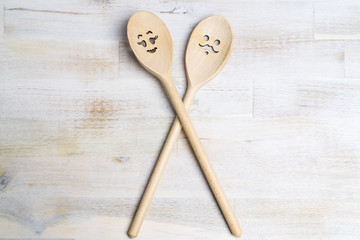 Wooden spoon with funny faces, woman and man, on wooden background