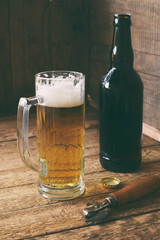 Mug of beer, bottle on wooden background. Photographed with natural light