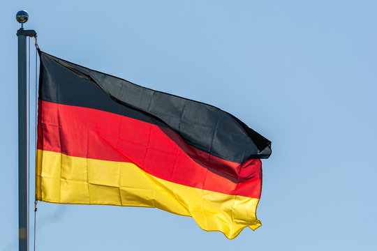 Im Wind wehende Flagge der Bundesrepublik Deutschland vor blauem Himmel
