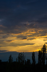 Landscape with dramatic light - beautiful golden sunset with saturated sky and clouds.