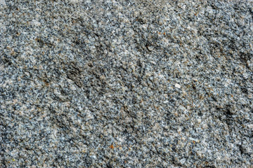 Abstract background. Close-up view of natural rought untreated grey granite texture.