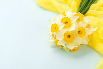 Daffodil bouquet with yellow textile decoration on blue pastel background with copy space.