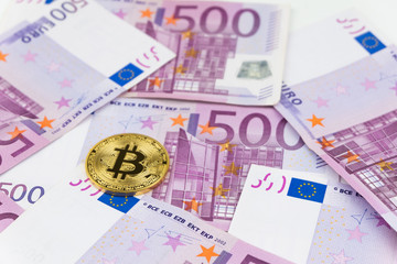 Golden bitcoin on pile of five hundred euro banknotes background. Cryptocurrency.