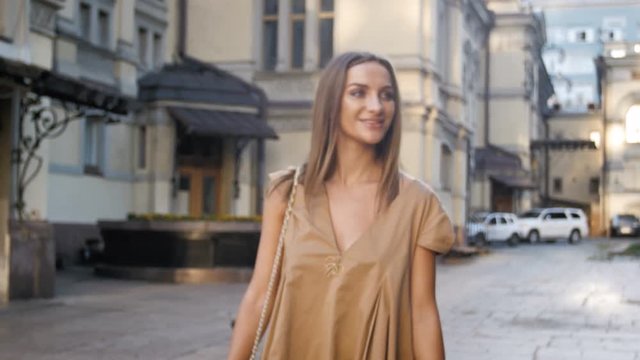 4k footage of beautiful smiling woman walking on street of old city at bright sunny day