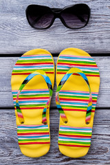 Yellow flip flops and sunglasses. Pair of sandals and spectacles.