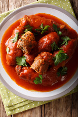 Italian meat roll braciole stuffed with parsley and cheese in tomato sauce close-up. Vertical top view