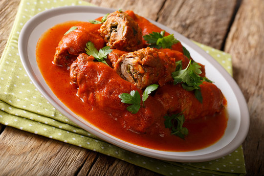Italian food: beef steak stuffed with parsley and parmesan cheese in tomato sauce close-up on a plate on a table. horizontal