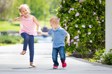 Young Sister and Brother Holding Hands And Running At The Park