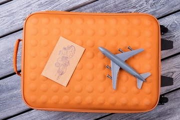 Top View Travel Stuff On Wood. Orange suitcase, post mail and toy grey airplane.