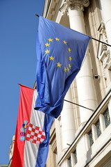 Flaga Unii Europejskiej oraz Chorwacji wiszą razem na scianie budynku, na zewnątrz, powiewają na...