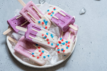 Yogurt popsicles topped with white chocolate and american stars sprinkles