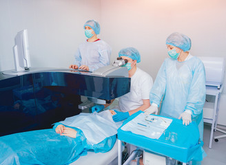 Laser vision correction. A patient and team of surgeons in the operating room during ophthalmic surgery. Eyelid speculum. Lasik treatment.