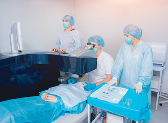 Laser vision correction. A patient and team of surgeons in the operating room during ophthalmic...