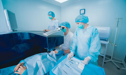 Laser vision correction. A patient and team of surgeons in the operating room during ophthalmic...