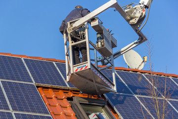 A german worker is mounting a photovoltaic system on a roof