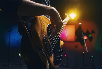 bass guitar in the hands of a musician - obrazy, fototapety, plakaty